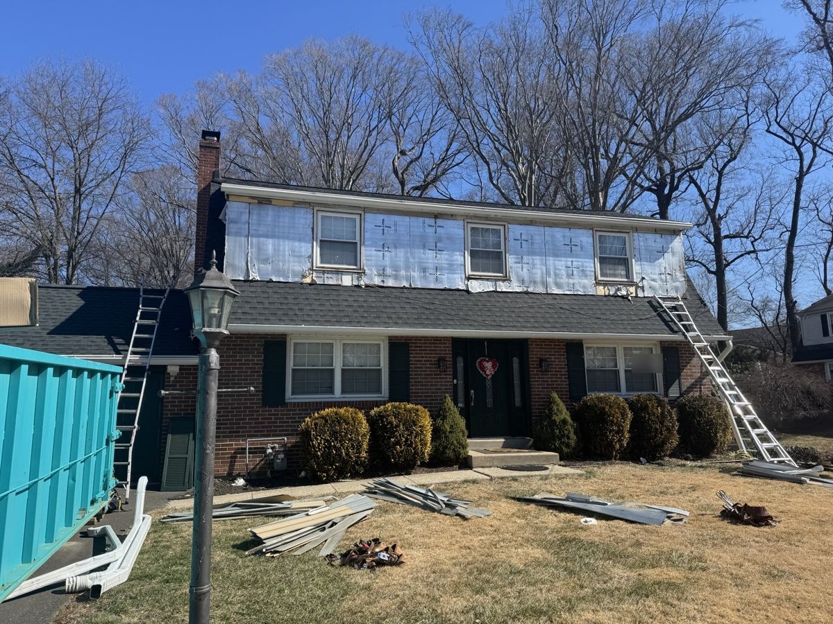 Two-story home with new charcoal shingles and the old siding stripped from the upper walls