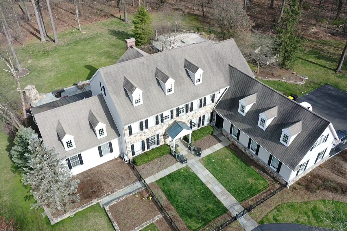 Aerial view of a Doylestown colonial with weathered roof sections in mismatched shades before replacement