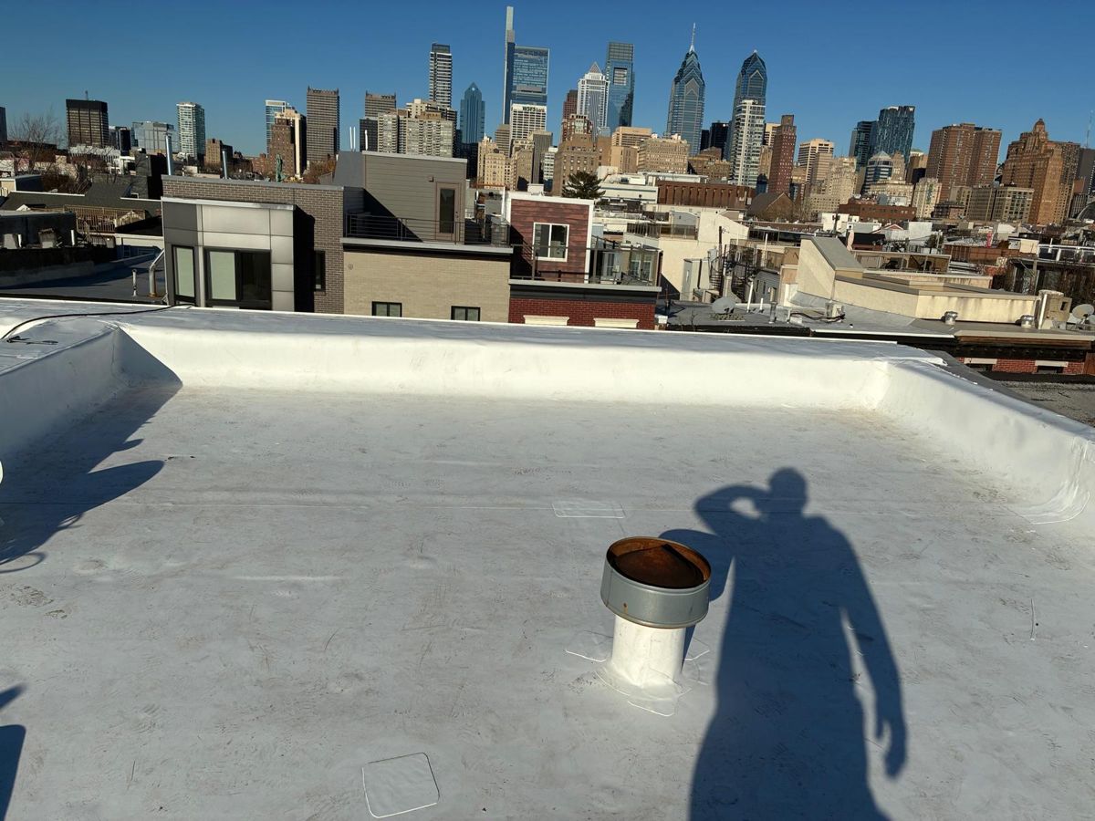 Finished white TPO rowhome roof with the Philadelphia skyline behind it