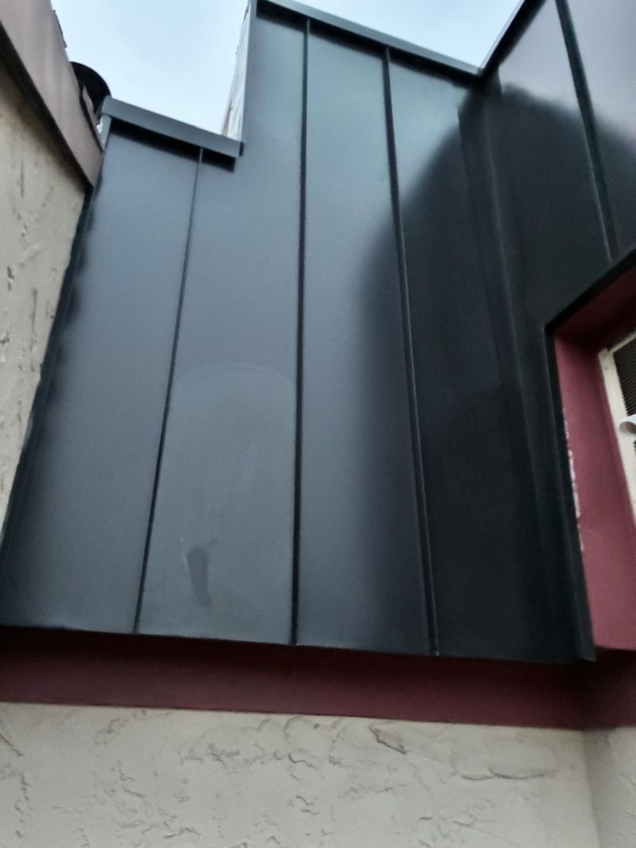 Matte-black standing-seam metal panels on a steep rowhome mansard in Philadelphia